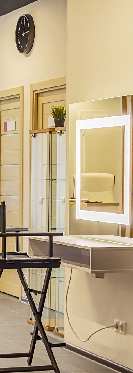 Schminkstuhl vor beleuchtetem Spiegel Schminkstuhl vor beleuchtetem Spiegel in einem modernen Salon mit Wanduhr.