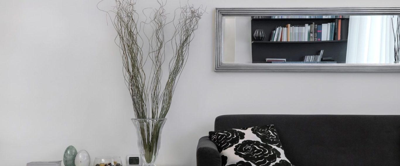 modernes Wohnzimmer Ein modernes Wohnzimmer mit schwarzem Sofa, Spiegel und Dekorationszweigen.