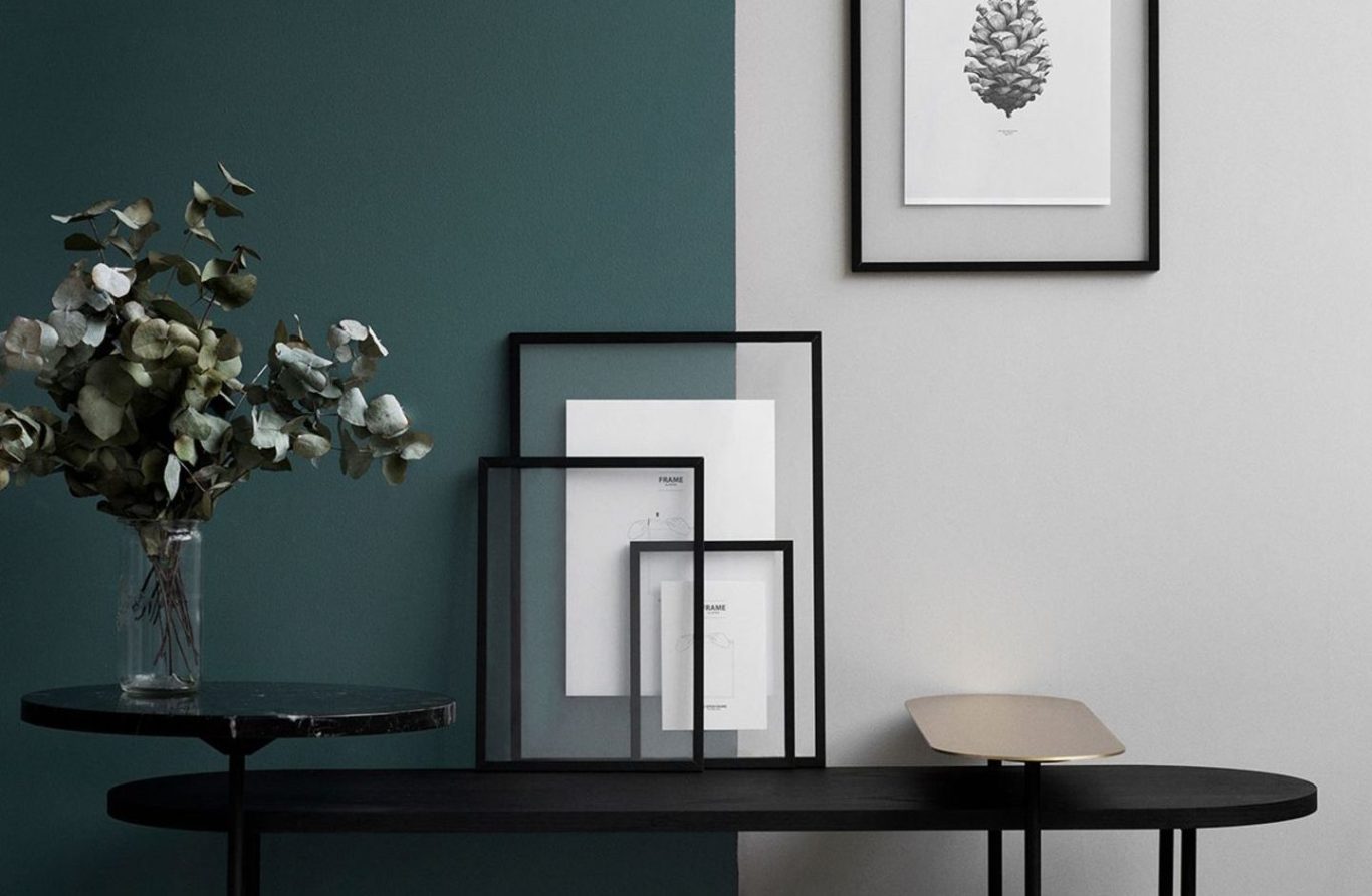 Beispielbild Akzentwand mit Einrichtung Moderner Tisch mit gerahmten Bildern und einer Glasvase mit Blumen auf einer zweifarbigen Wand.