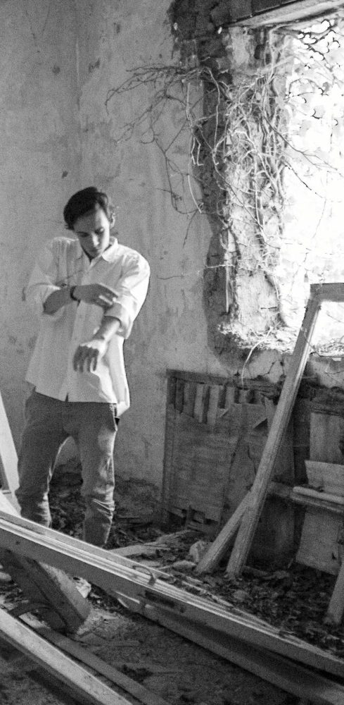 Ein Mann steht in einem alten Raum umgeben von Holzresten - eine Baustelle