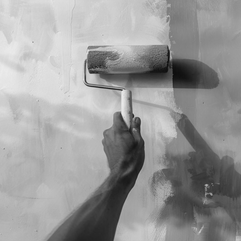 Farbrolle über eine Wand, Eine Hand führt eine Farbrolle über eine Wand, die frisch gestrichen wird.