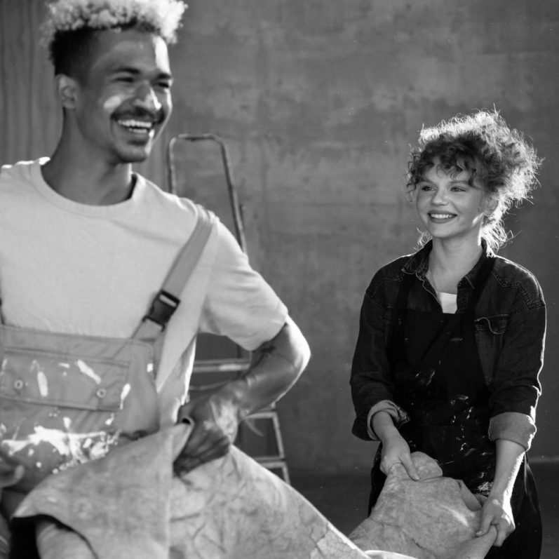 Ein lächelnder Mann und eine Frau arbeiten zusammen an einem kreativen Projekt.