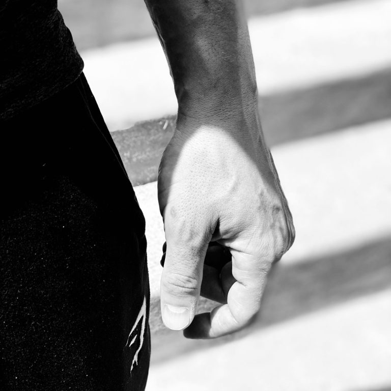 Nahaufnahme einer Hand,  auf einem leicht gestreiften Hintergrund.