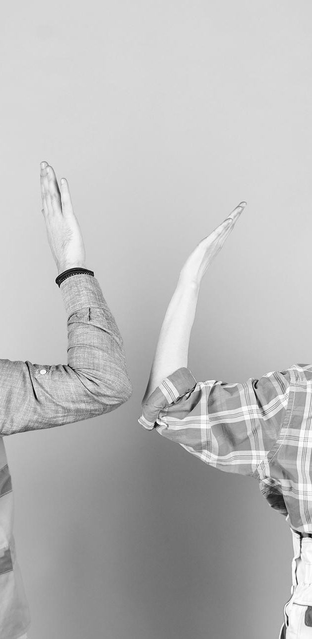 Zwei Hände heben sich nach oben, eine aus einem karierten Hemd, die andere aus einem T-Shirt.