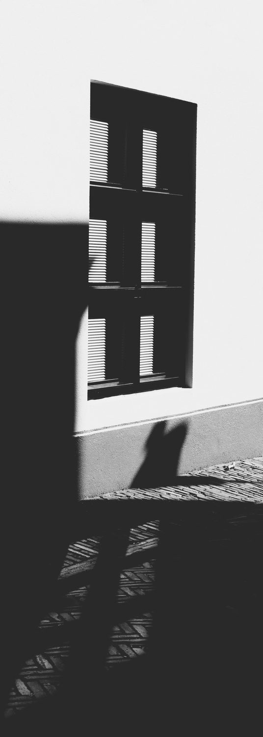 Außenfassade Ein Fenster mit ruhigem Schattenwurf auf einen hellen Boden.