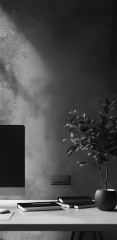 Moderner Schreibtisch mit Computer, Pflanzen und sanftem Licht in Schwarz-Weiß.