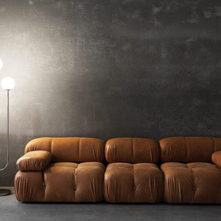 braunes, gepolstertes Sofa steht vor einer grauen Wand Ein braunes, gepolstertes Sofa steht vor einer grauen Wand, daneben eine Stehlampe.