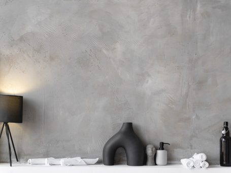 Akzentwand Innen Moderne Wand in Grau mit dekorativen Objekten und einer Lampe auf einem Tisch.