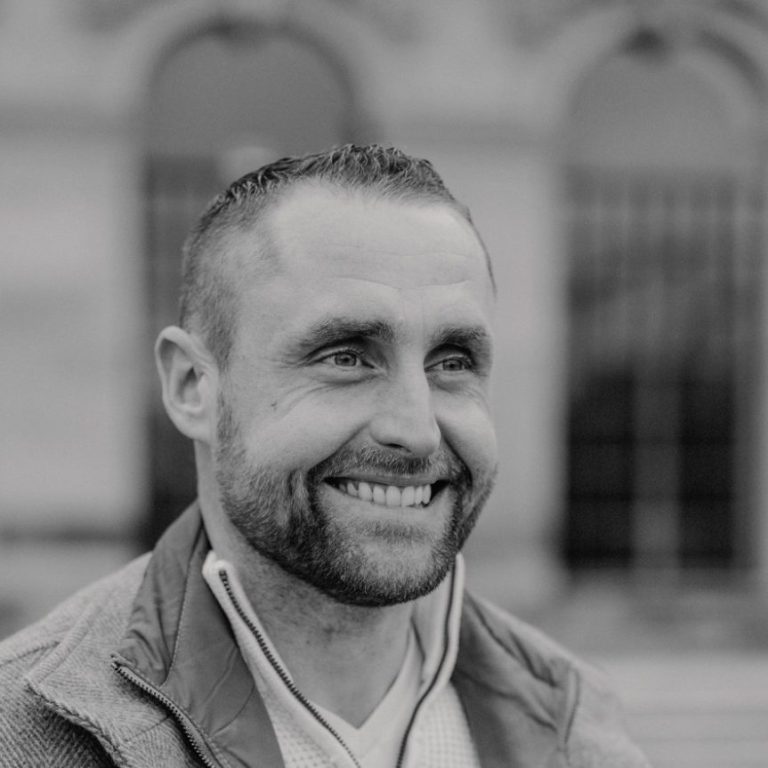 Brian Krüger Malermeister Brian Krüger mit kurzem Haar und Bart lächelt freundlich in die Kamera.